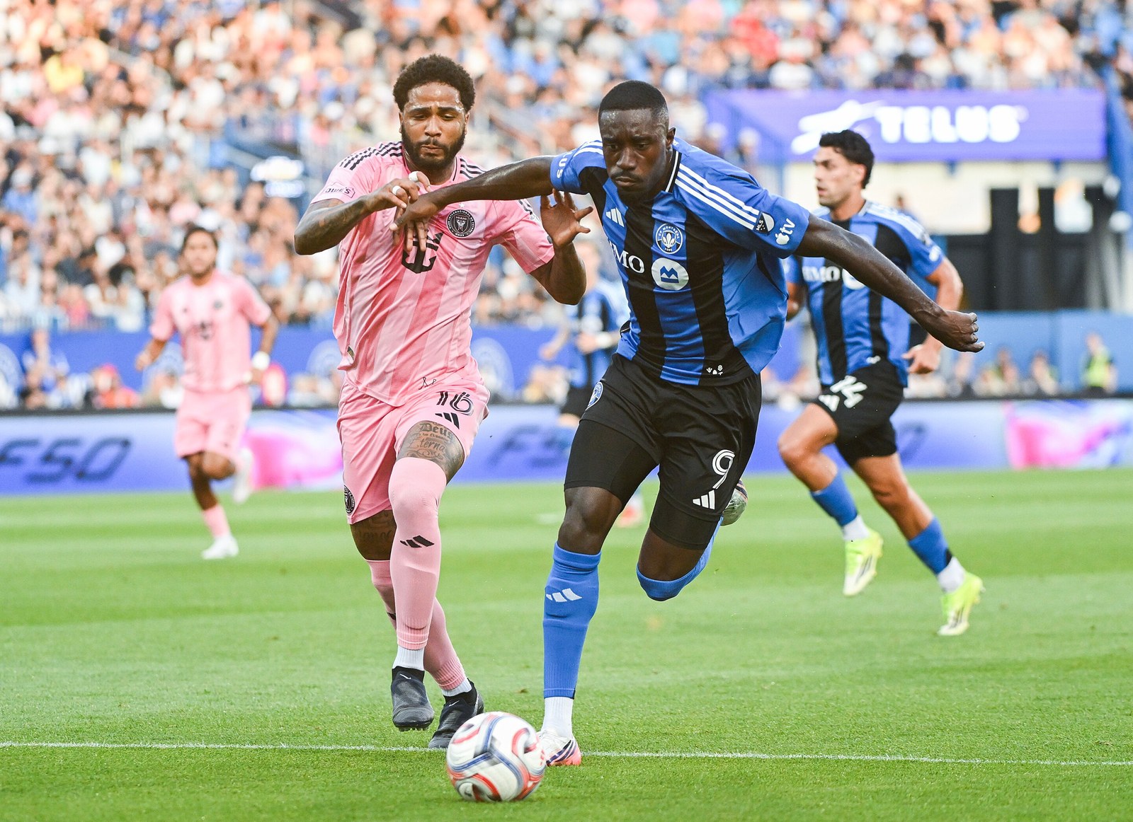 A CF Montreal forward holds off an Inter Miami defender at Saputo Stadium