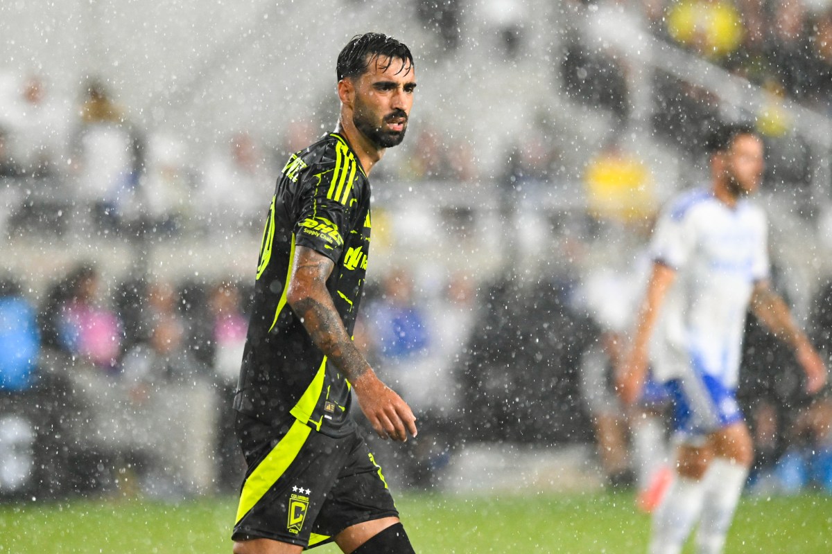 Columbus Crew midfielder controls the ball in heavy rain during an MLS match