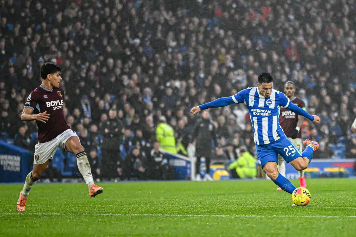 Brighton forward shoots under pressure from an Aston Villa defender in the rain
